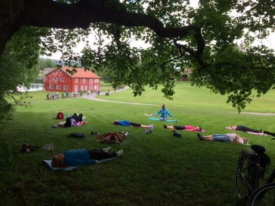 Bilde av kursdeltakere som ligger på gresset og gjør øvelse på samling på Domkirkeodden